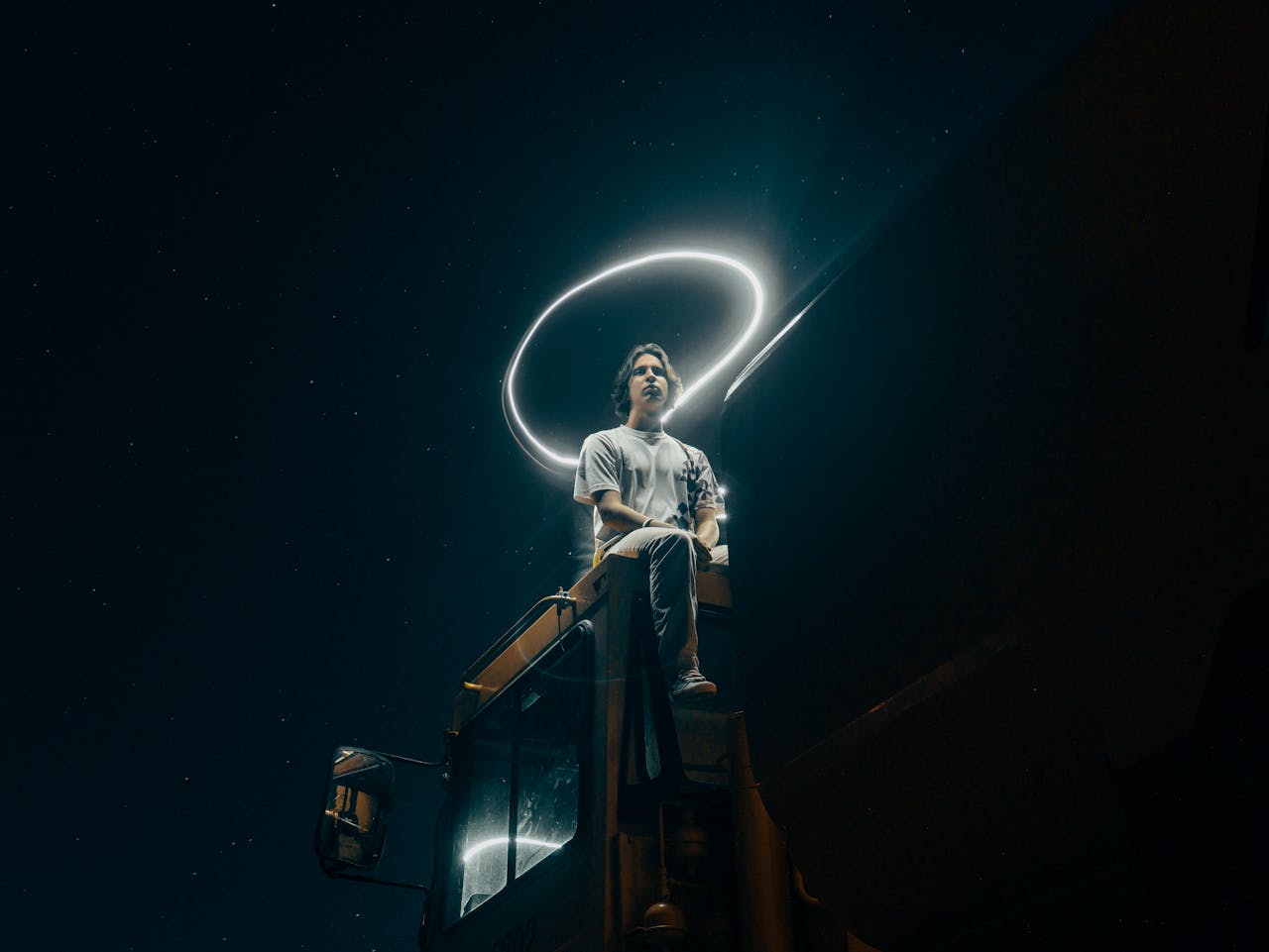 services-01 A man sits on a truck, surrounded by a light halo under a starry sky.